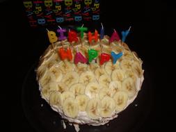 cream cake decorated with candles and bananas