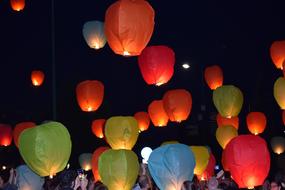 lot of colorful sky lanterns over crowd of people
