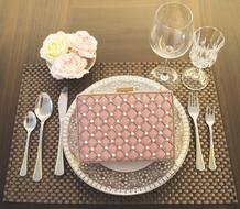 luxury women’s purse on plate near cutlery and glasses