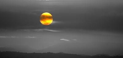yellow Sun in grey sky over rural landscape