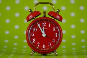 red alarm clock on a green background