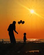 father with balloons and daughter by the sea