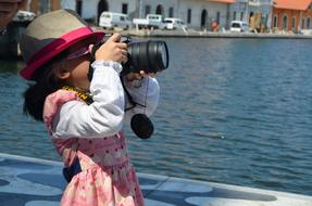 cute little girl with a camera by the sea