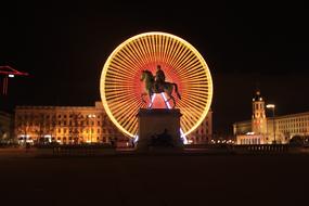 sculpture against the backdrop of a luminous Ferris wheel