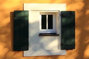 small window of a house with green shutters