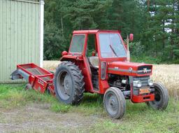 big red tractor on a farm near a field