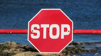 stop sign on the fence by the sea