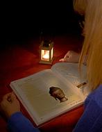 girl reading a book by the candle