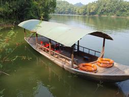 a beautiful boat with a roof in the lake.