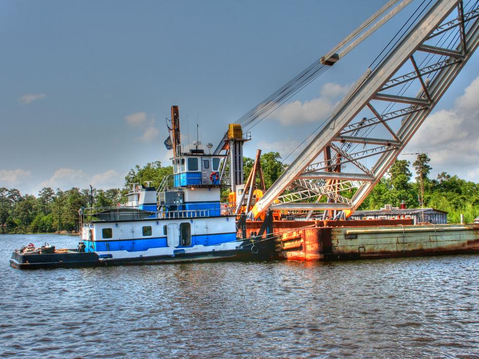 Colorful boat in the port with green plants, under the sky with clouds