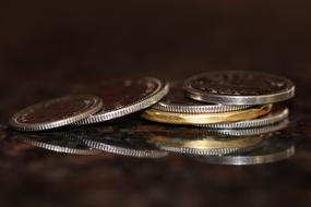 Close-up of the colorful, shiny metal coins with reflections, at dark background