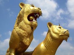 Animal Lion Gold statues at blue sky background with white clouds
