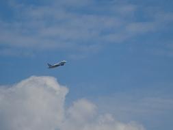 Flying aircraft in the beautiful, blue sky with white, fluffy clouds