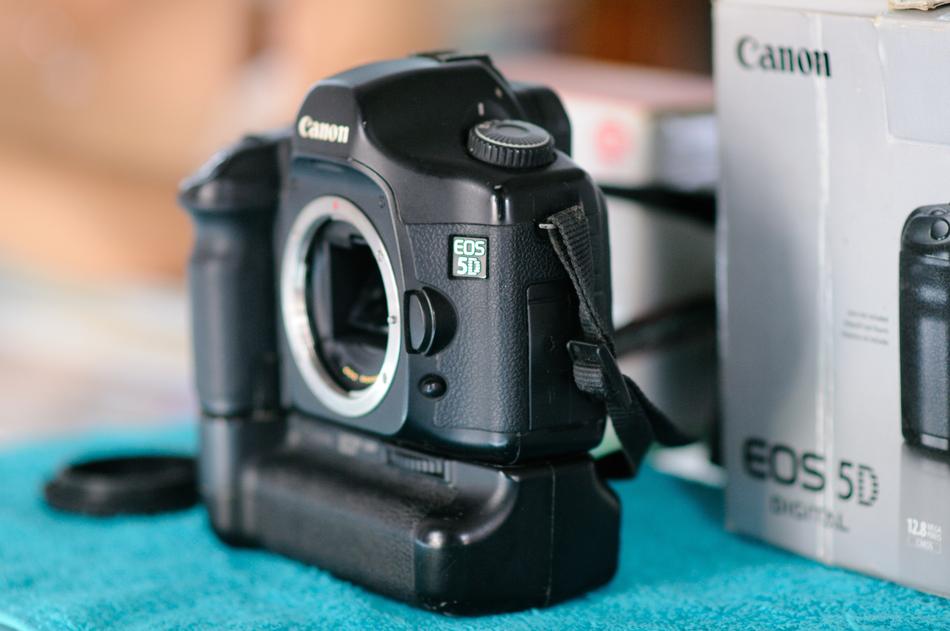 Black 'Canon' camera, near the white box, on the turquoise surface
