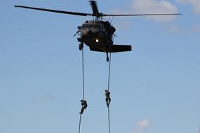 military helicopter in the sky with ropes