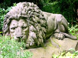 Stone Figure Lion among the vegetation in the park