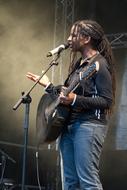 young man with dreads singing at stage microphone
