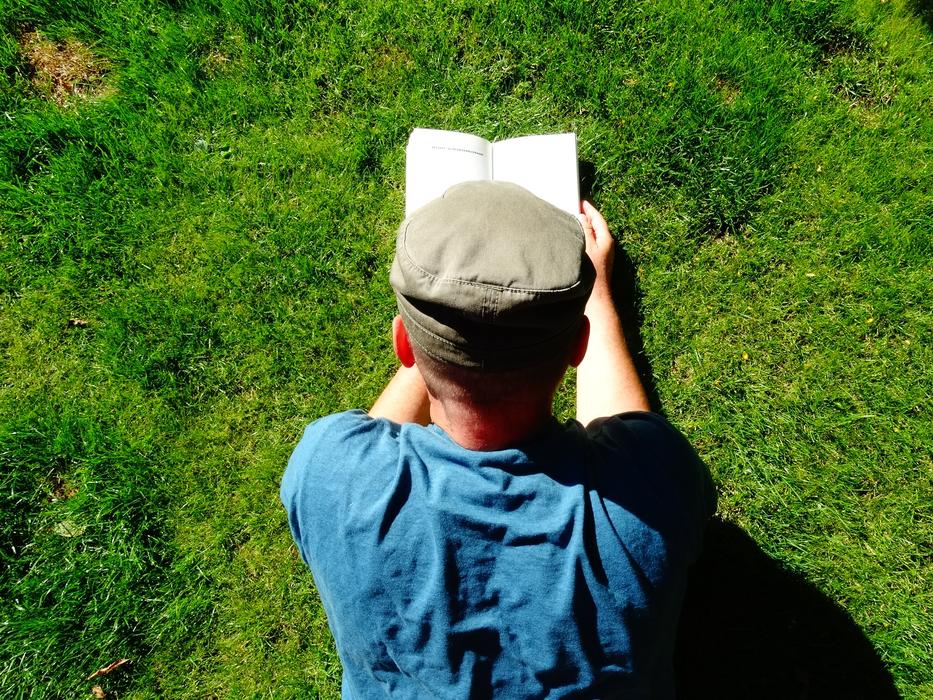 man reading a book on the lawn on a sunny day