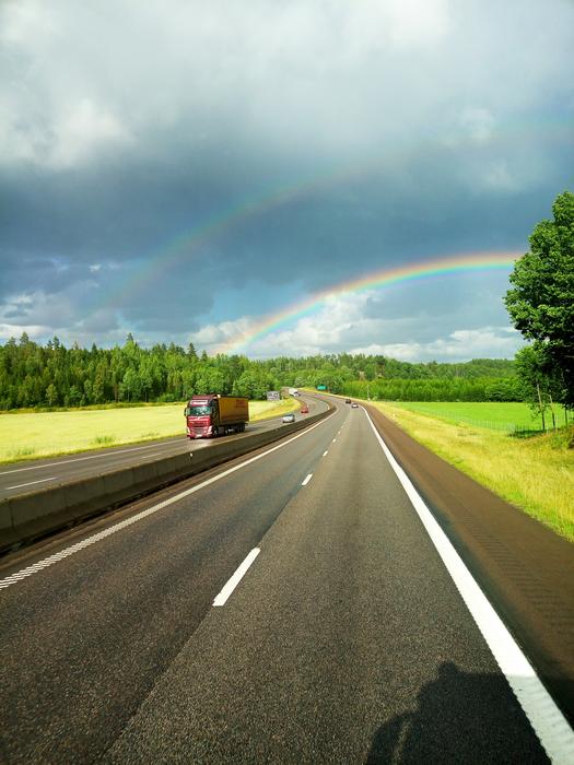 rainbow in the distance by the road