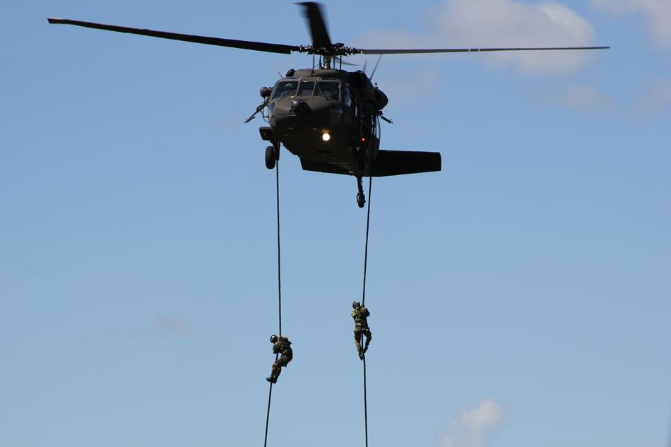 military helicopter in the sky with ropes