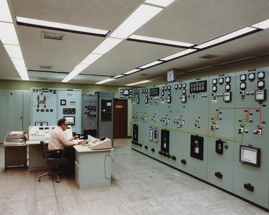 Man, sitting in the control room of the electrical substation, with lights