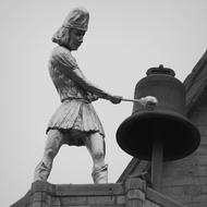 sculpture of a man ringing a bell
