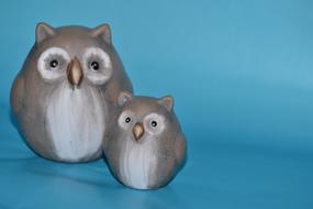 two gray ceramic owls on a blue background