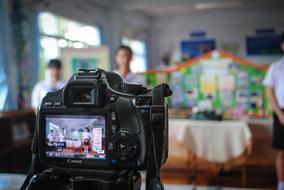 Taking photo of the people, near the colorful decoration, on the black "Canon" camera with the buttons