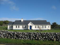 long white village House behind Stone wall, Ireland