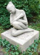 Beautiful, white grave stone with the sculpture, among the green plants