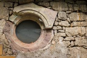 round window with mesh in old stone wall