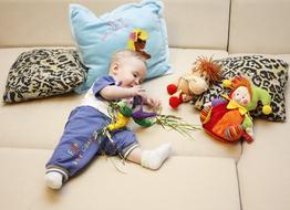 baby boy plays with soft toys on sofa