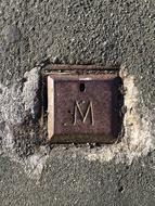 iron button with the letter m in the wall