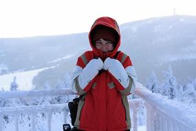 Girl in warm clothes among the snow in the winter on beautiful landscape