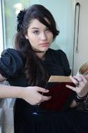 beautiful girl in a black dress reading a book