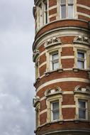 Beautiful, red architecture with the windows, at cloudy sky on background in London, England, UK