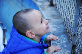 boy in blue jacket near the fence