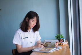 Asian student woman, reading a magazine on the wooden table