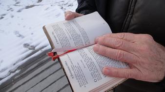 Person reading bible in the hands, near the snow