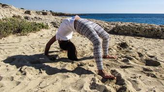 girl doing exercises upside down on the beach