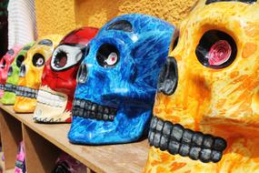 bright painted human skulls, souvenirs on shelf, Colombia, BoyacÃ¡, RÃ¡quira