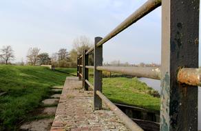 Metal fence along the river with the green shore