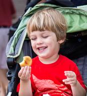 Blonde boy eating donut and smiling