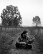 Young Man plays guitar on path in countryside