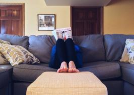 Male, reading a magazine, while sitting on the sofa