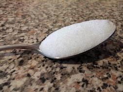 sugar in a spoon on the kitchen table close-up