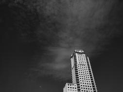 Black and white low angle shot of the high-rise building, under the cloudy sky