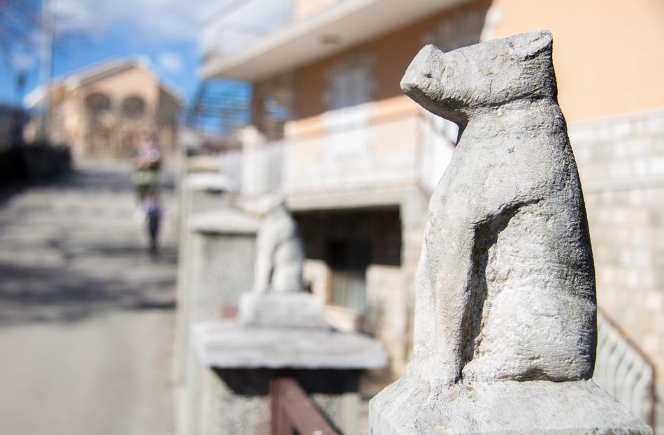 aged stone animal figures on fence at gate