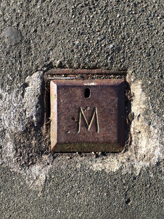 iron button with the letter m in the wall