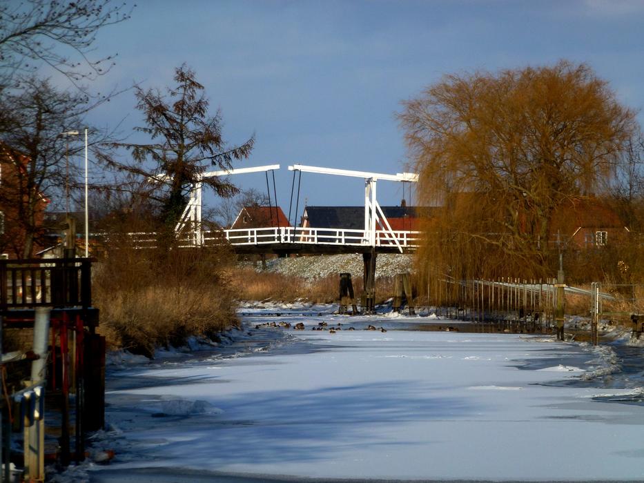 white bridge across frozen river in countryside